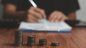 coin stacks in front of a person writing in a notebook
